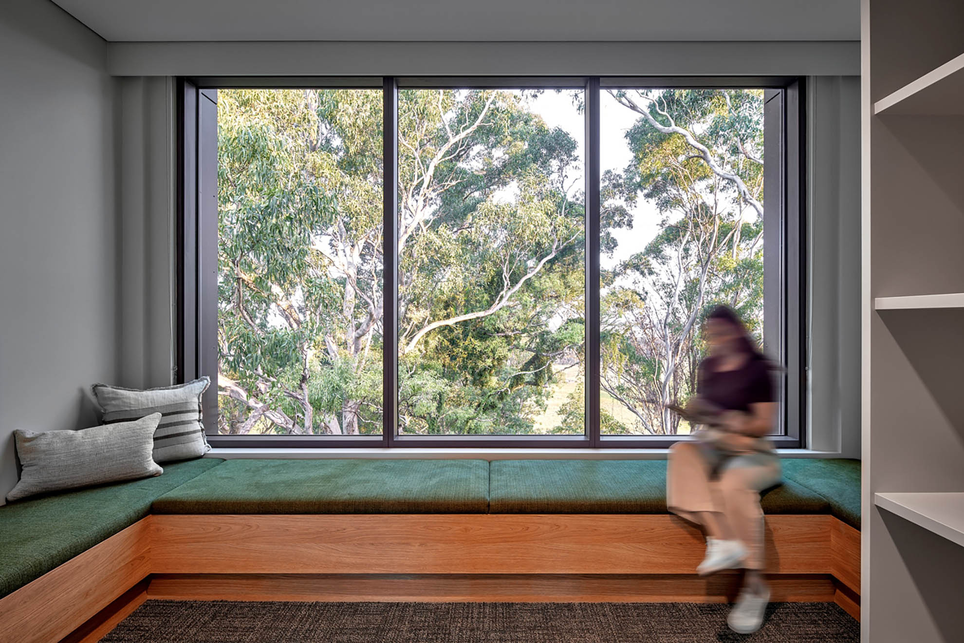 St John of God Richmond Hospital redevelopment young woman reads a book on bench seating in front of a window