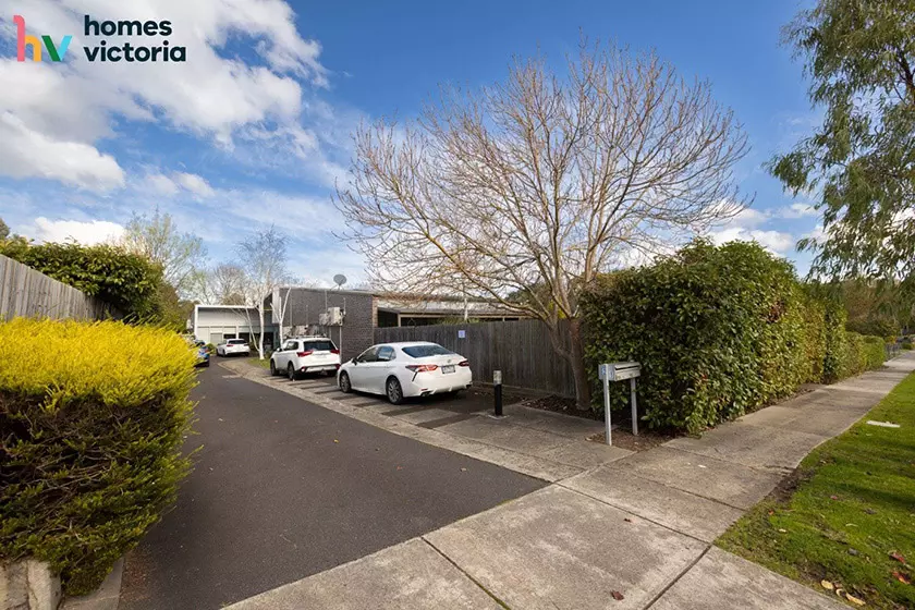 A house with a privacy fence, shrubs and greenery outside.